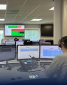 Medewerker bij Alarm Meldnet actief in meldkamer vol schermen en monitoring.